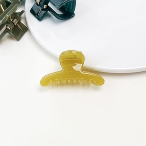 Detail of small translucent amber hair claw clip with jelly texture on white background