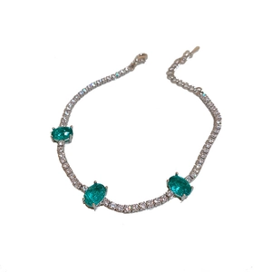 Silver bracelet with three oval green crystals and sparkling pavé stones on a white base
