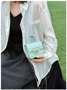 Detail of mint green quilted jelly bag with gold twist handle and chain strap