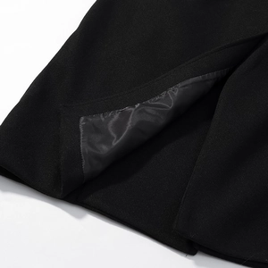 Detail view of the split hem and charcoal satin lining on a black woolen coat