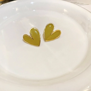 Détail de boucles d'oreilles cœur jaune moutarde avec bord doré sur assiette