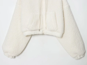 Detail of white sherpa fleece jacket featuring elastic hem and side pockets