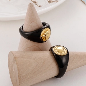Detail of vintage heart and star patterns on black resin rings over wooden stand