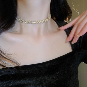 Close-up of a gold mesh choker necklace with sparkling crystals on a model's neck