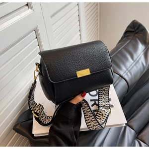 Détail du sac bandoulière en cuir noir avec large sangle à motif chevrons élégante