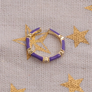 Macro detail of purple enamel open ring with gold trim and micro zircon inlay on linen