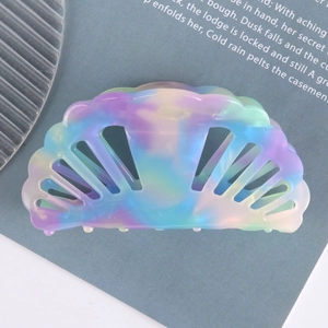Detail view of shell-shaped hair claw with dreamy gradient rainbow colors on magazine