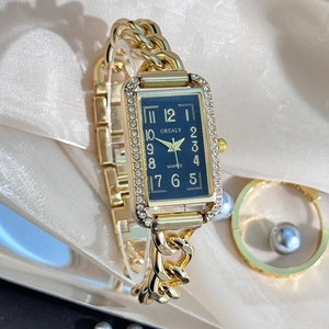 Detail of square gold watch with blue sunray dial and rhinestone bezel on silk fabric