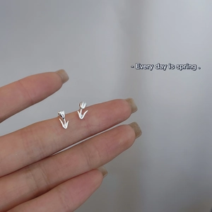 Macro shot of silver tulip stud earring held in hand to show delicate floral details