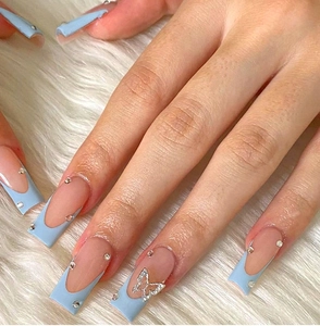 Detailed view of light blue French tip nails with silver butterfly charms and rhinestones