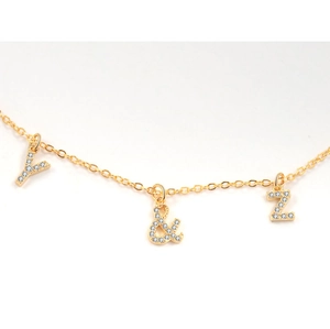 Close-up of golden necklace with micro-pave zircon Y, ampersand, and Z letter charms