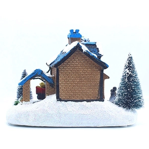 Vue détaillée d'une maison de Noël miniature en résine avec toit enneigé et petit sapin