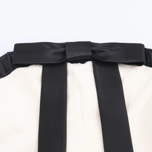 Elegante abito bianco senza spalline con un fiocco decorativo in raso nero a contrasto