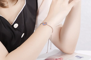 Bracciale in oro rosa con ciondolo a corona in smalto blu indossato al polso femminile