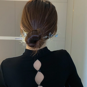 Minimalist silver butterfly hair stick with fluid lines shown on a model's dark hair bun