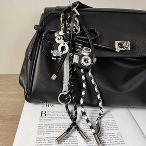 Dettaglio borsa in pelle nera con cordino intrecciato, bambola Mickey e ciondolo fotocamera
