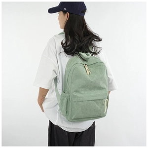 Close-up of light green corduroy backpack showing textured fabric on a model