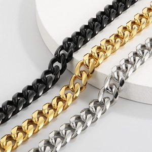 Three Cuban link chains in black, gold, and silver finishes displayed on a white podium