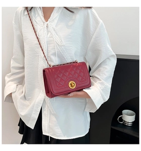 Detail of red quilted leather shoulder bag featuring golden round twist lock and chain strap