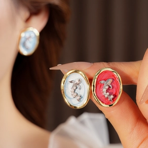 Detailed macro view of vintage goldfish enamel earrings with pearl and gold frame