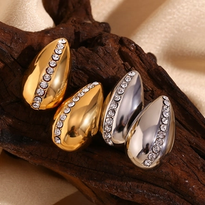 Macro view of teardrop stud earrings with pave rhinestones on wood and satin background