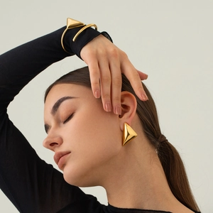 Dettaglio di orecchini a triangolo e bracciale in acciaio inossidabile placcato oro 18k