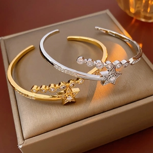 Detail of star-shaped zircon open bangles in gold and silver finish on a gift box
