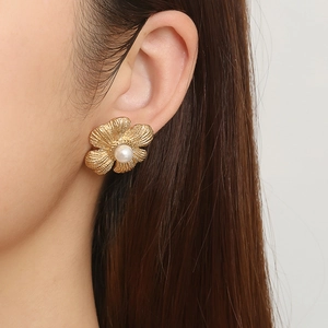 18 Karat vergoldete Edelstahl-Blumenohrringe mit Perle am Ohr eines weiblichen Modells