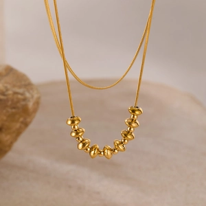 Macro shot of gold-plated snake chain necklace with flat disc bead accents on stone