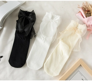Flat lay of cotton socks with large sheer tulle bows in black white and beige colors