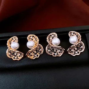 Elegant 18K gold plated hollow flower earrings with white pearls on a black display