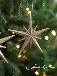 Macro view of a gold glitter star-shaped ornament hanging on a festive Christmas tree