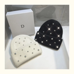 Detail of knitted beanie with sparkling rhinestones in black and white on a gift box