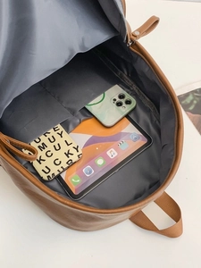Brown leather backpack with large capacity showing interior storage for tablets and phones