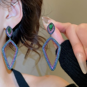 Close-up of geometric dangling earrings with emerald zircon and multicolor stones