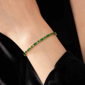 Detailed close-up of emerald and round cut zirconia tennis bracelet on a model's wrist