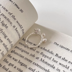 Detalle del anillo de plata S925 con perlas y textura vintage sobre un libro