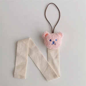 Detail of beige herringbone hairclip organizer strap with a pink plush bear head decoration