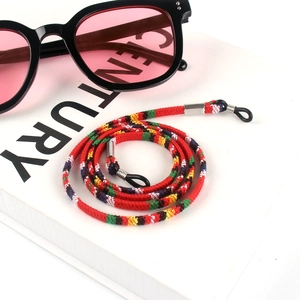 Close-up of bohemian woven eyeglass strap in red ethnic pattern on a white prop book