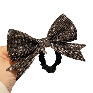 Elegant black rhinestone bow hair tie with pleated fabric band shown on hand