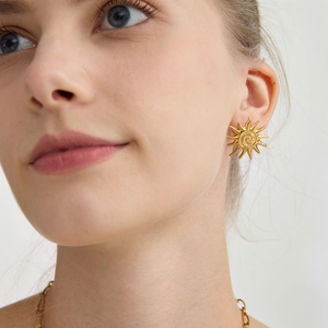 Boucles d'oreilles soleil en acier inoxydable plaqué or 18 carats portées par un mannequin