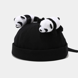 Detail of a black skullcap featuring two cute plush panda bears on top with adjustable strap