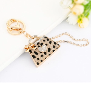 Detail of leopard print handbag keychain with golden bow and sparkling heart charm