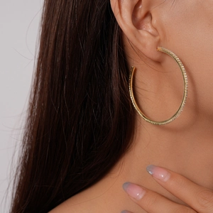 Close-up of elegant gold hoop earrings with pavé diamonds worn by a female model
