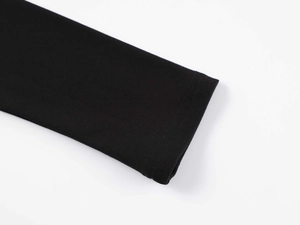 Gros plan du détail des poignets à double couture sur un haut noir à manches longues