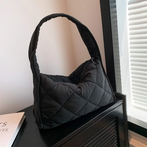 Detailed close-up of a black quilted nylon shoulder bag with soft diamond pattern texture