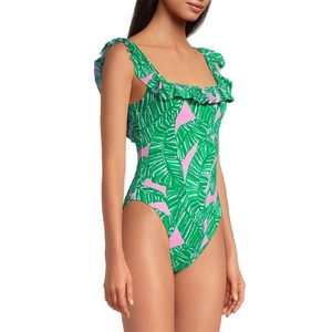 Detail of ruffled shoulder straps and green tropical palm leaf print on pink swimsuit