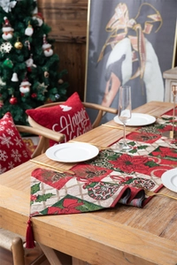 Christmas table runner with floral patchwork patterns and red tassels in a festive setting
