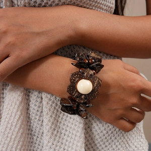 Detail of bohemian wood bead and coconut shell flower bracelet worn on a wrist