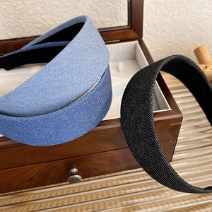 Trois serre-têtes larges en denim bleu clair, bleu foncé et noir sur une boîte à bijoux